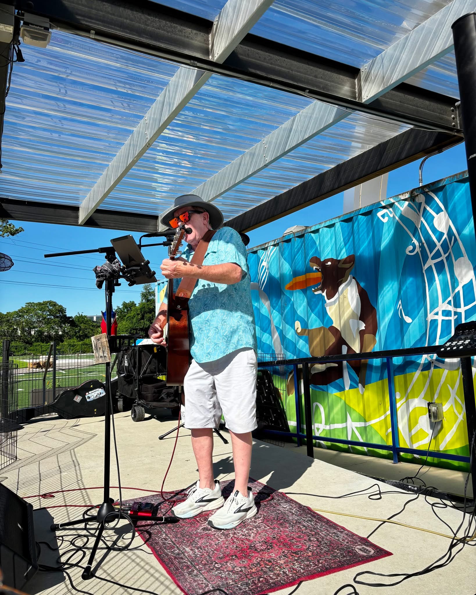 Mel Hughes performing live in front of a bright mural